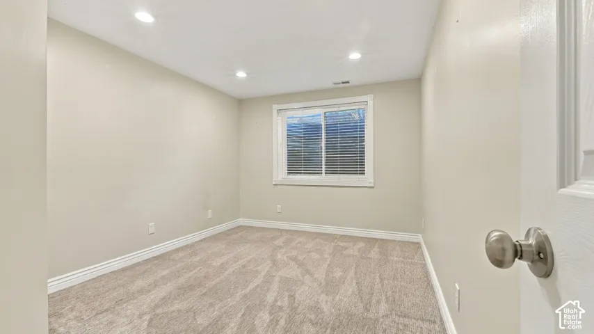 Interior room featuring neutral-toned carpeting, recessed lighting, and a window with horizontal blinds