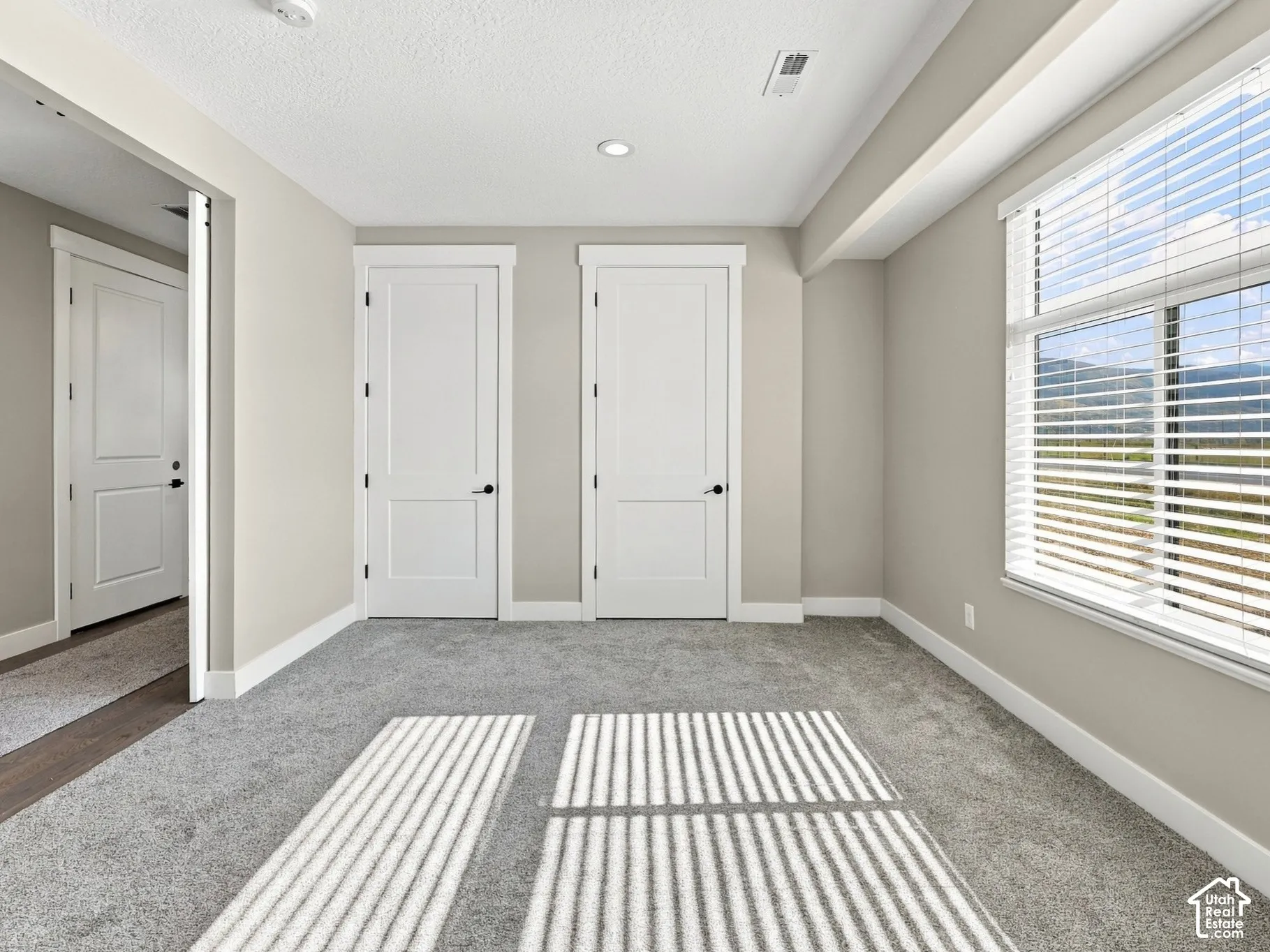 Neutral-toned interior featuring wall-to-wall carpeting, two-panel interior doors, recessed lighting, and a large window with horizontal blinds