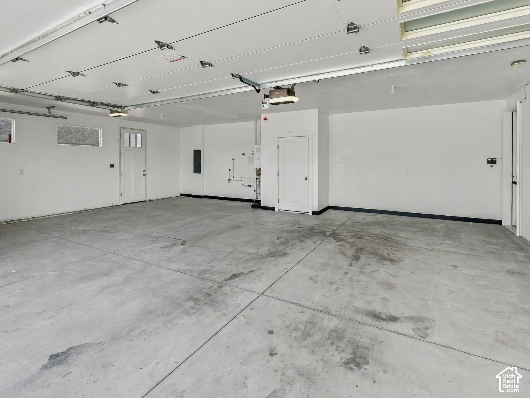 Three-car garage featuring a concrete floor, high ceilings with overhead door tracks, inset lighting, and multiple access doors