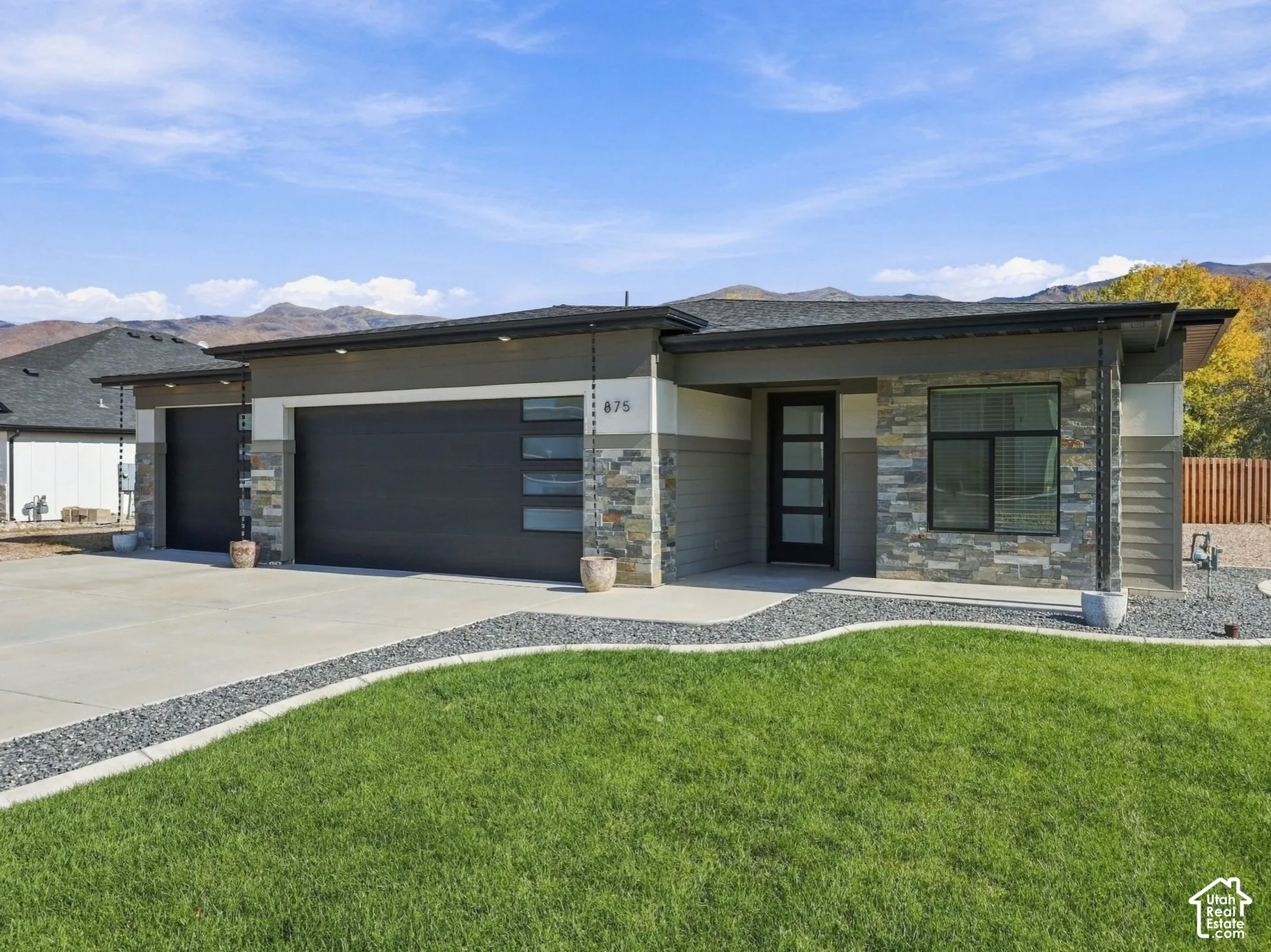 Contemporary exterior featuring horizontal siding, stacked stone accents, a three-car garage with modern glazing, and a full-light entry door