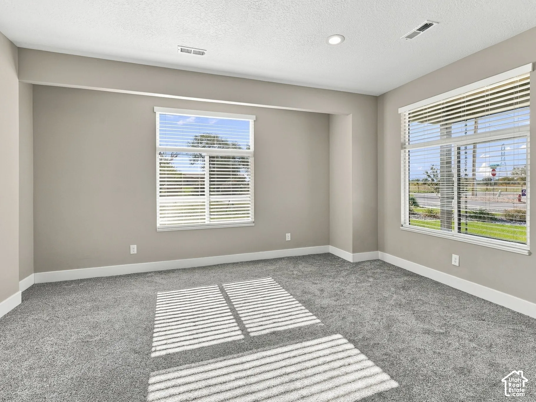 Neutral interior featuring wall-to-wall carpeting, recessed lighting, and windows finished with horizontal blinds