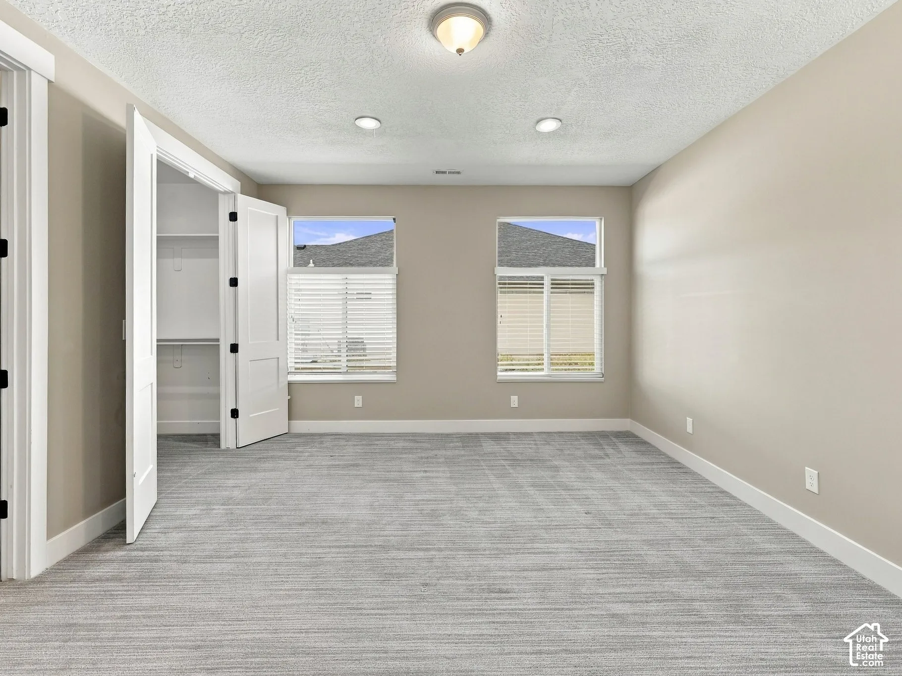 Room featuring neutral-toned wall paint, recessed lighting, carpeted flooring, and double-door closet storage