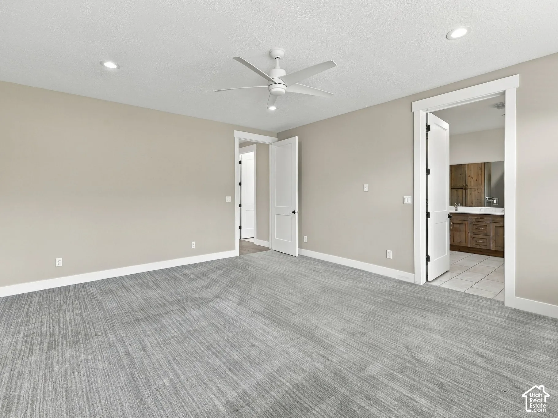 Neutral-toned interior featuring textured carpeting, a multi-blade ceiling fan, recessed lighting, and white casing trim