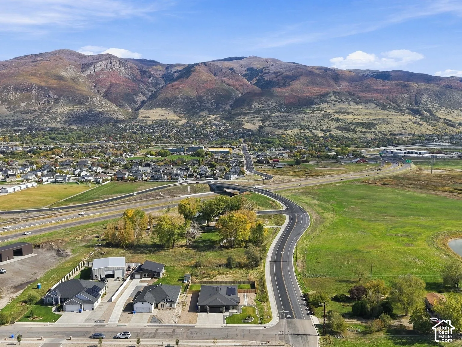 Aerial perspective featuring expansive mountainous surroundings, open green space, and proximity to regional thoroughfares