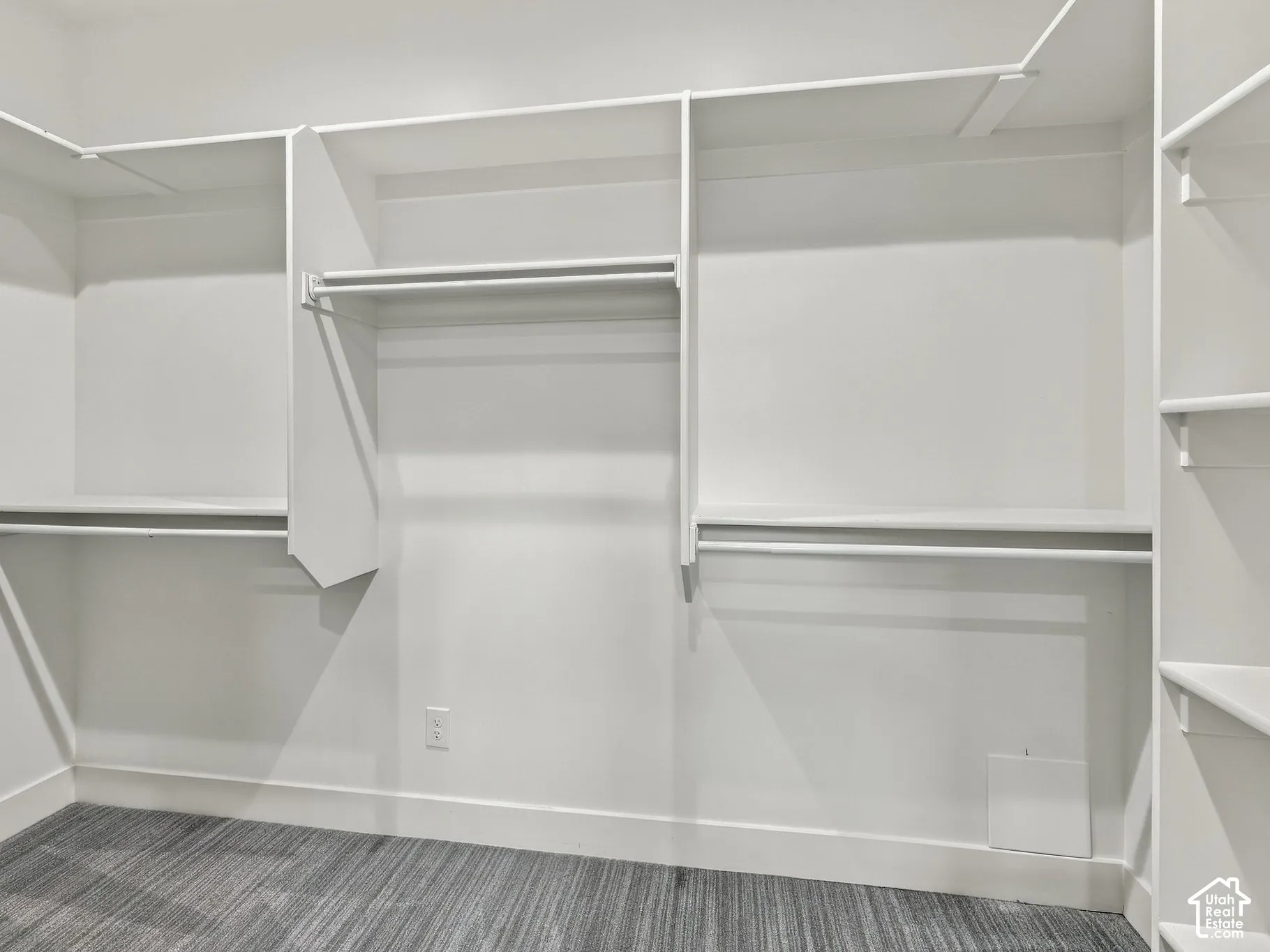 Walk-in closet featuring tiered shelving, integrated hanging rods, and patterned carpeting