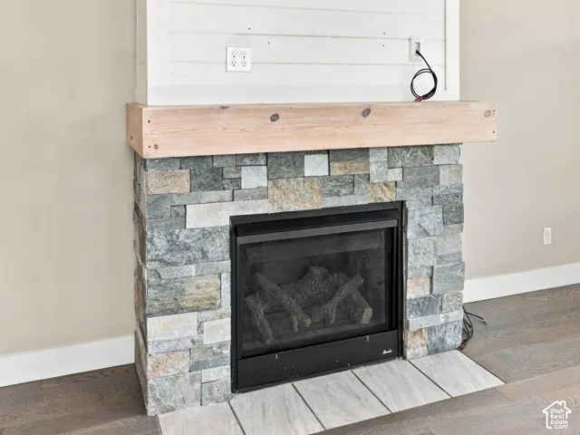 Fireplace featuring a multi-tonal stacked stone surround, natural wood-finish mantle, shiplap detailing, and tile hearth