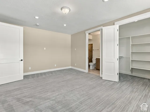 Room featuring grey carpeting, recessed and flush-mount lighting, two-panel interior doors, and a built-in closet with integrated shelving