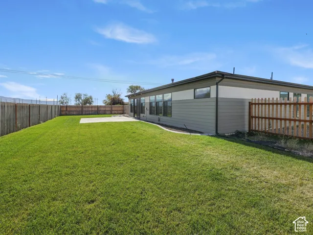 Backyard featuring a manicured lawn, concrete patio, and full-perimeter wood fencing