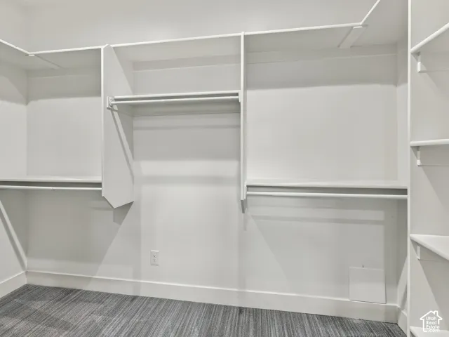 Walk-in closet featuring tiered shelving, integrated hanging rods, and patterned carpeting