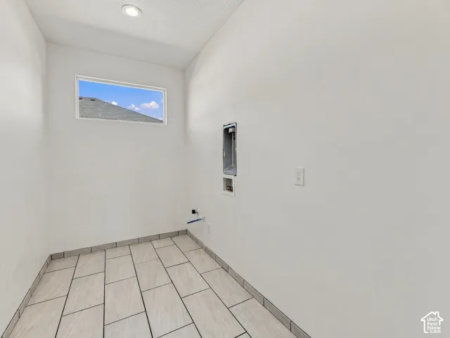 Utility space featuring large-format rectangular floor tile, recessed ceiling lighting, and a horizontal window