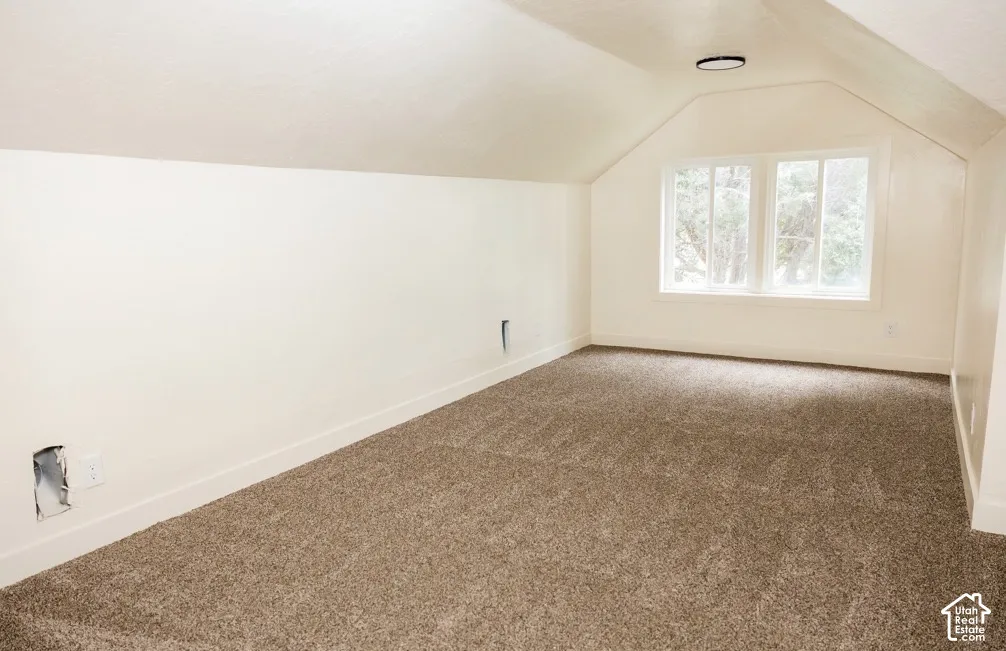 Sloped ceiling interior featuring wall-to-wall carpeting, dual-pane windows, and a circular flush-mount ceiling light