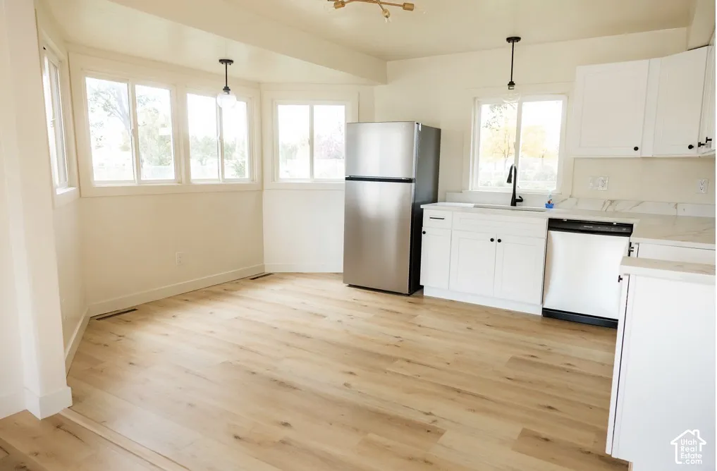 Kitchen featuring wood-finish flooring, white cabinetry, stone-finish countertops, stainless steel appliances, and matte black hardware