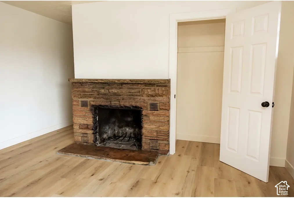 Floor-to-ceiling stone fireplace with a thick stone mantel and hearth, paired with wood-finish flooring and a walk-in closet featuring a six-panel door