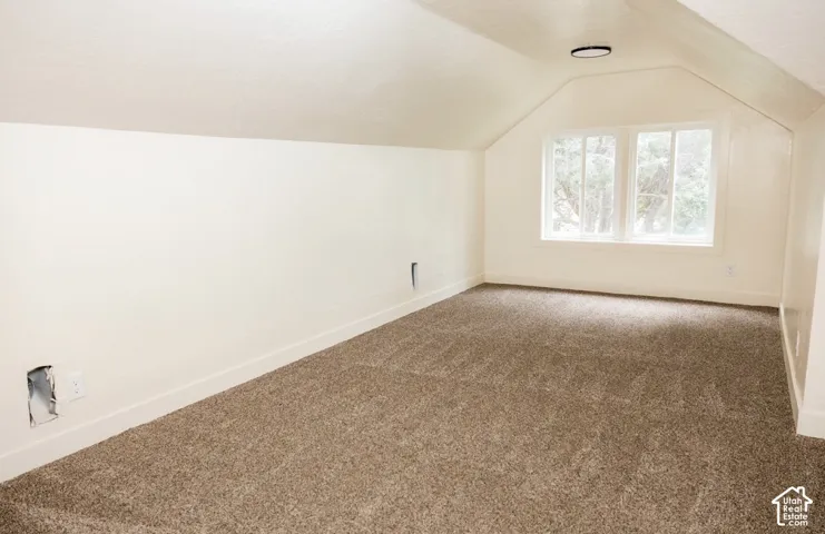 Sloped ceiling interior featuring wall-to-wall carpeting, dual-pane windows, and a circular flush-mount ceiling light
