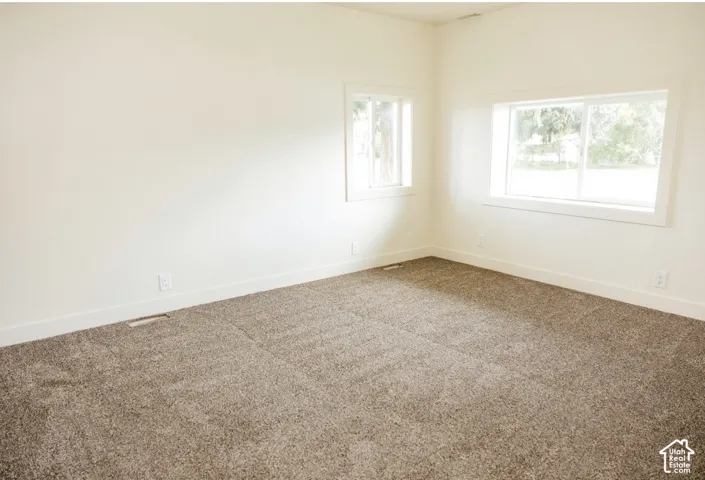 Neutral-toned wall-to-wall carpeting and dual sliding windows with white casing