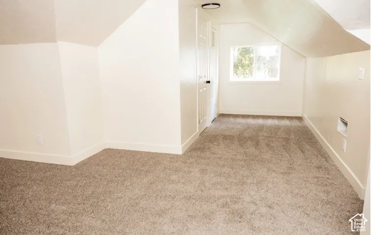 Neutral-toned carpeting, angled ceiling architecture, and a single sliding window