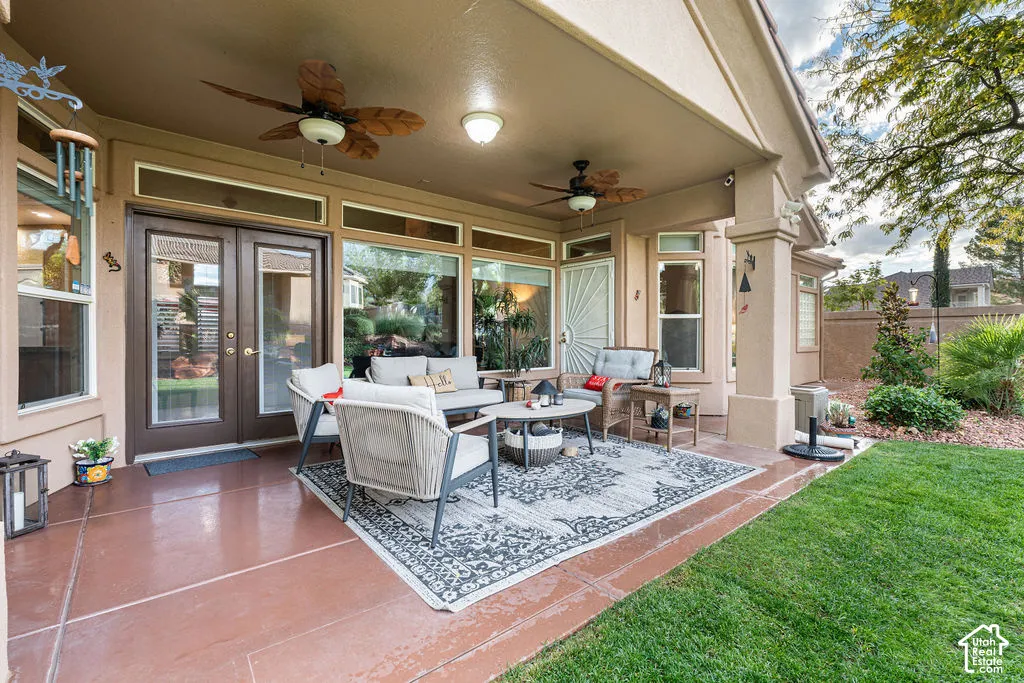 Covered patio featuring scored concrete flooring, dual ceiling fans, multiple transom windows, and recessed lighting