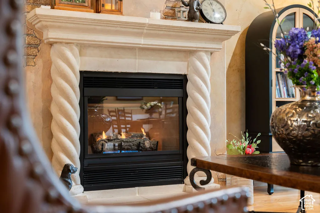 Fireplace featuring a stone-finish mantel with decorative spiral columns, textured wall surround, and a glass-front insert