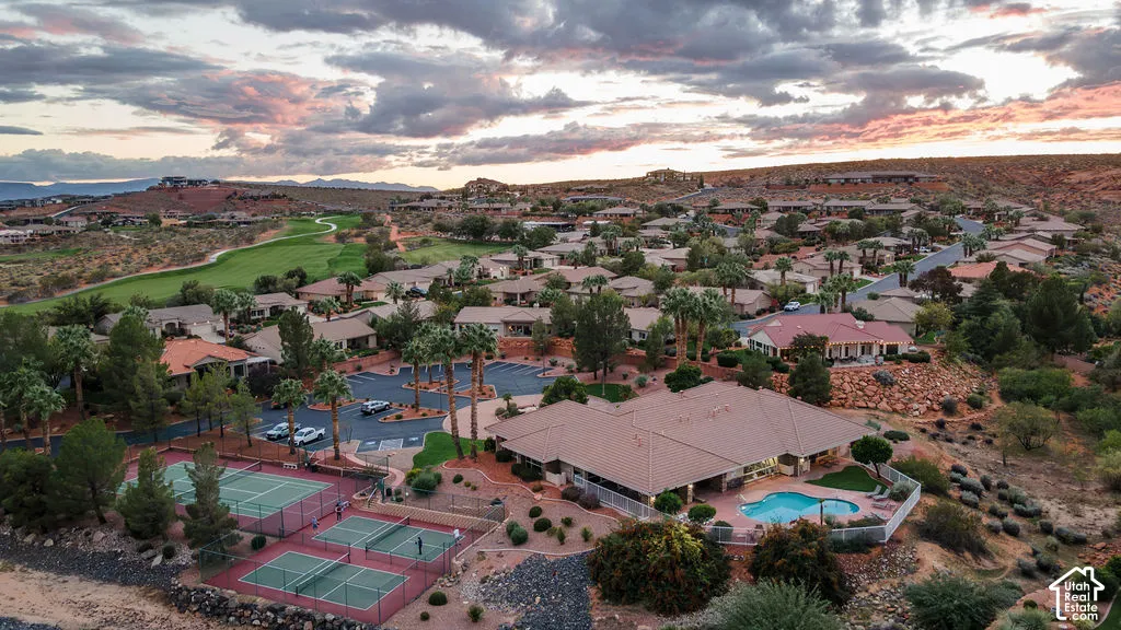 Aerial perspective featuring multiple tennis courts, a swimming pool with a surrounding patio, and expansive desert landscaping