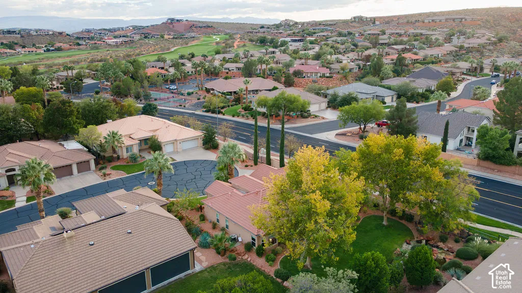 Aerial perspective of a suburban neighborhood featuring low-density residential architecture, tile roofing, manicured lawn areas, mature tree clusters, and desert landscape elements