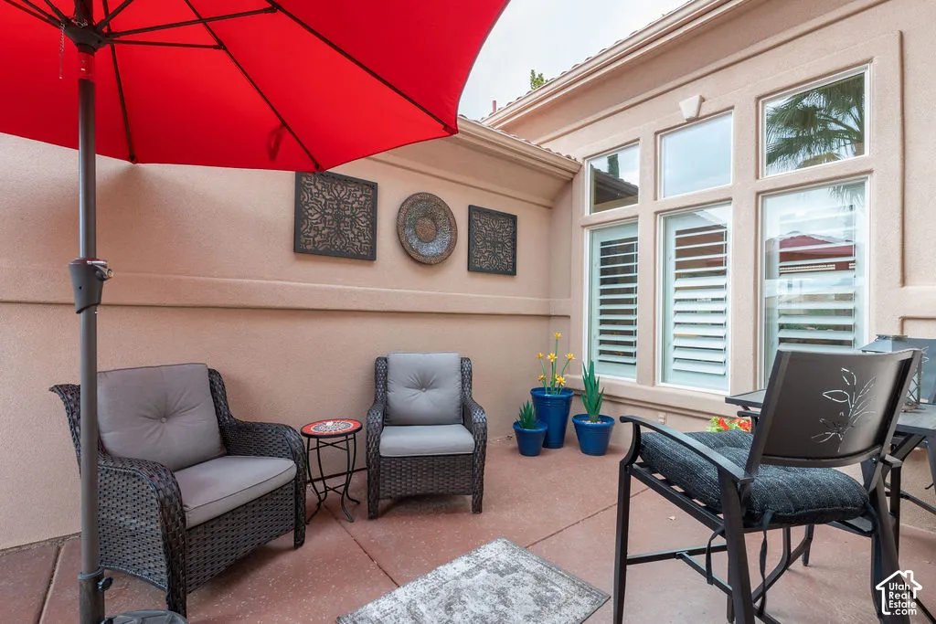 Stucco-walled courtyard patio featuring concrete surfacing and exterior windows with integrated plantation shutters
