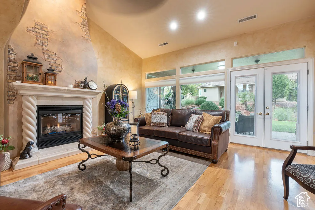Fireplace featuring decorative spiraled columns and a textured stone-finish chimney breast, wood-finish flooring, recessed lighting, and dual glass-paneled exterior doors with clerestory windows