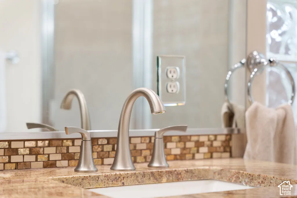 Brushed nickel widespread faucet, undermount sink, stone countertop, mosaic tile backsplash, and polished ring towel holder