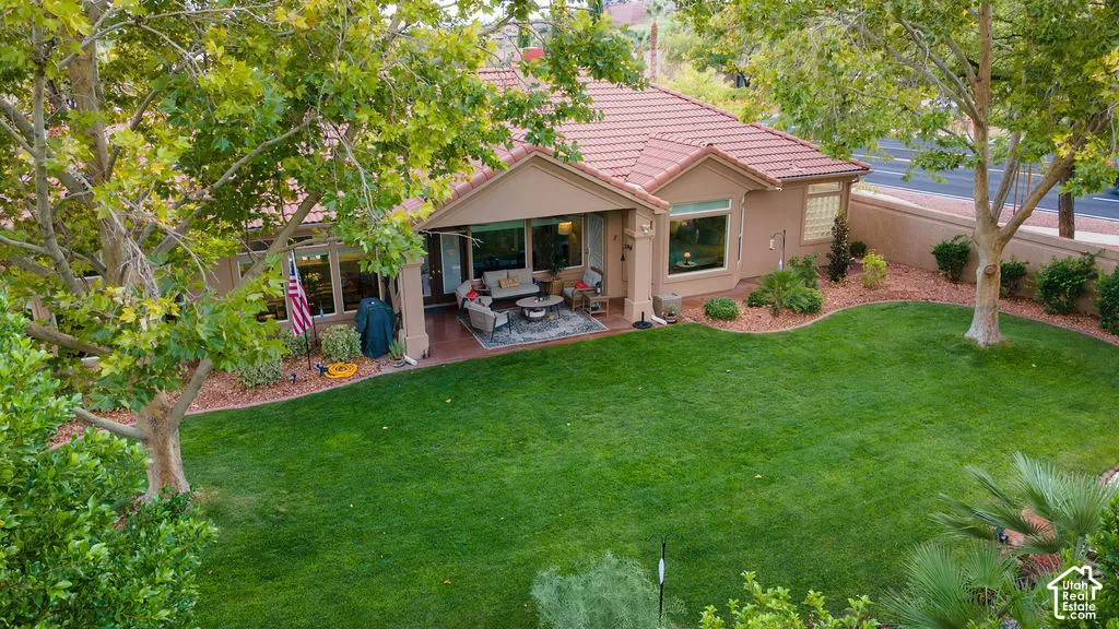 Backyard featuring a covered patio, expansive lawn, mature shade trees, and a perimeter masonry wall