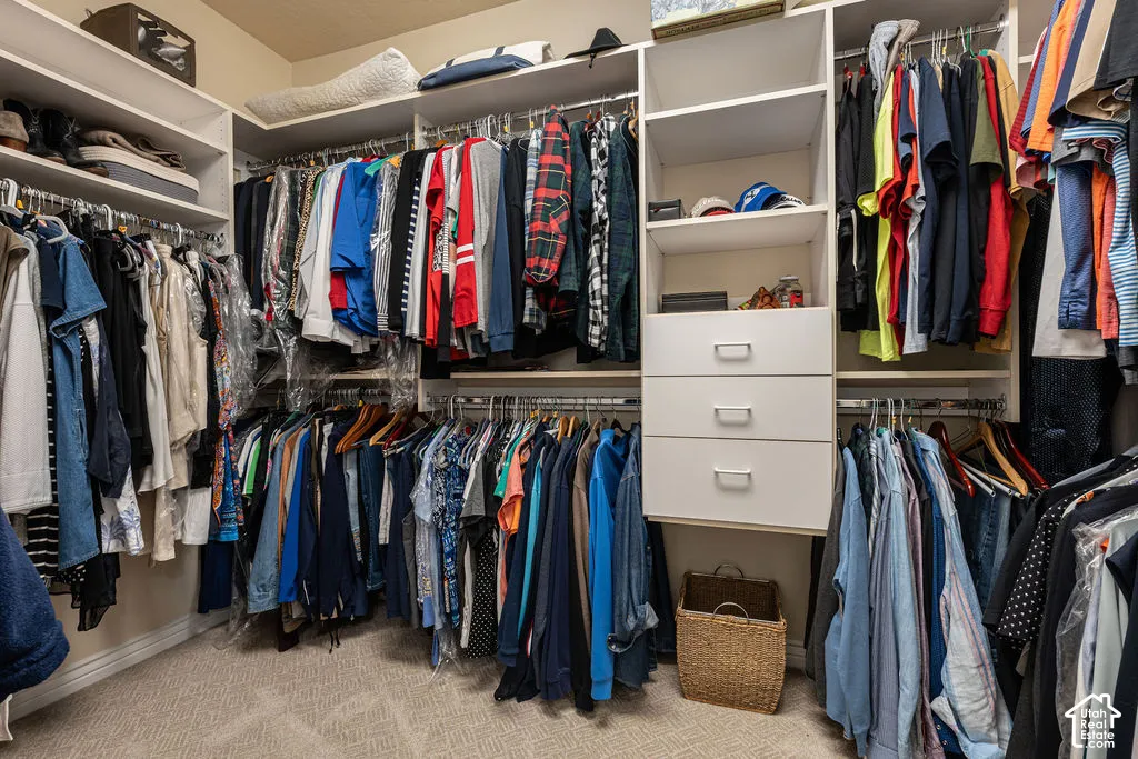 Walk-in closet featuring white built-in shelving, multiple hanging rods, and a stack of three integrated storage drawers