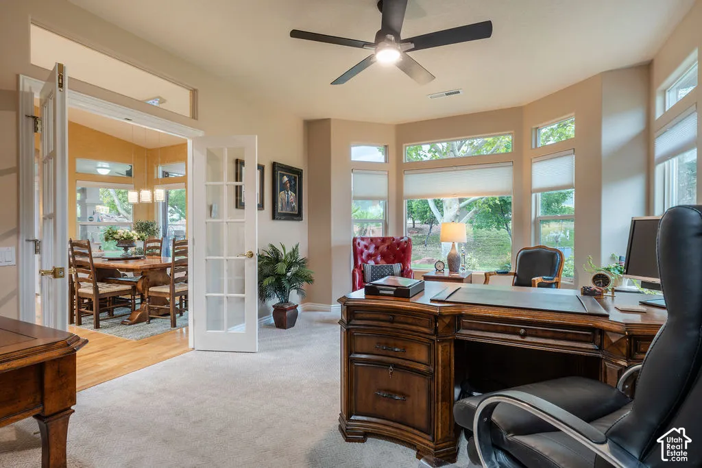 Bay window with multiple panes, ceiling fan with integrated lighting, glass-paneled double doors, and transom window