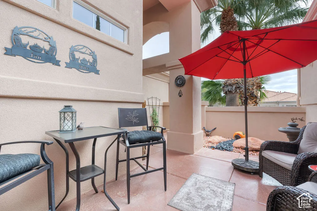 Covered patio featuring concrete flooring, stucco exterior walls, and a decorative perimeter wall