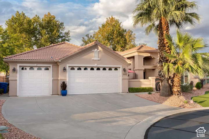 Single-story residence featuring a tile roof, stucco exterior, three-car garage, and desert-inspired landscaping