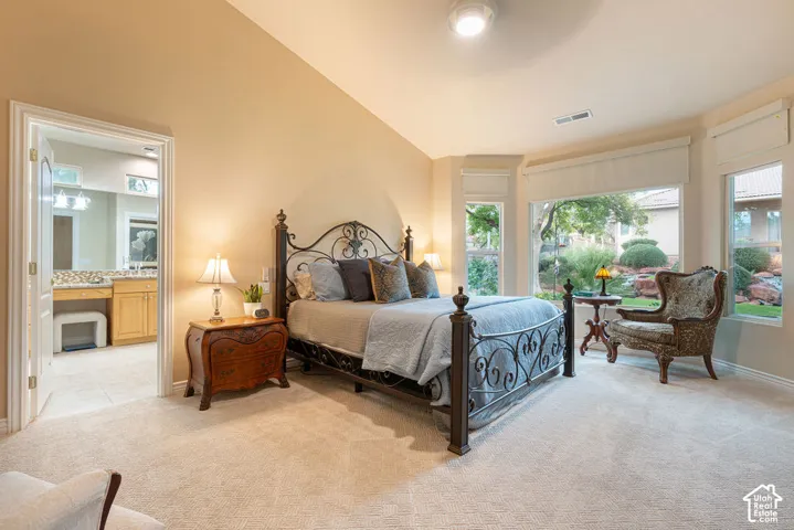 Bedroom featuring vaulted ceilings, neutral carpeting, large bay window, and built-in vanity cabinetry