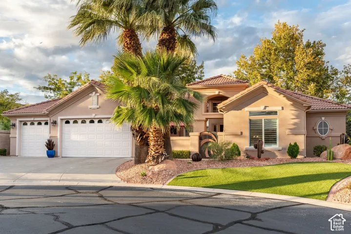 Stucco exterior with a tiled roof, multi-car garage, gated entry, and manicured landscaping