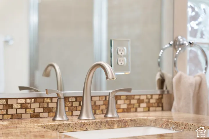 Brushed nickel widespread faucet, undermount sink, stone countertop, mosaic tile backsplash, and polished ring towel holder