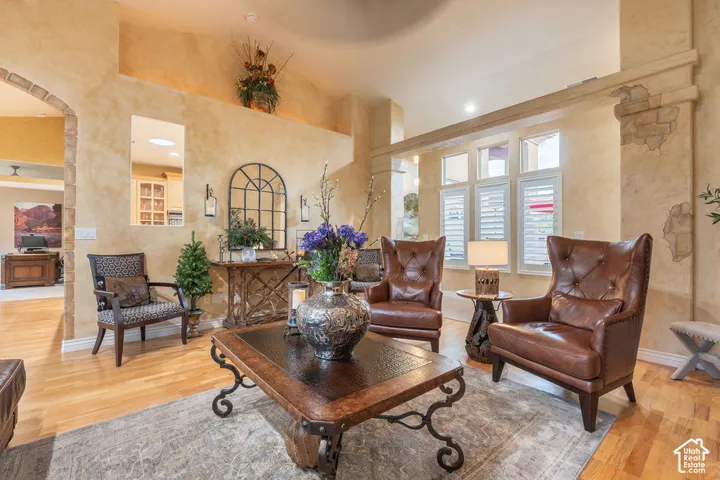 Vaulted ceilings, textured wall finishes with stone accents, arched entryway, and multi-pane windows with integrated shutters