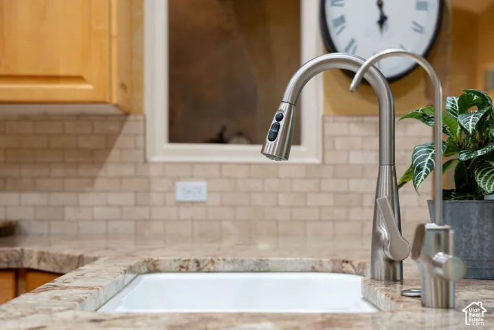 Undermount sink with stone countertop, stainless steel pull-down faucet, auxiliary filtered water faucet, and subway tile backsplash