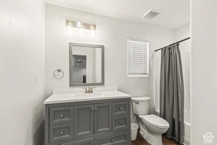 Bathroom featuring a vanity with dark-finish cabinetry, white countertop, integrated rectangular sink, framed mirror, and three-light wall-mounted fixture