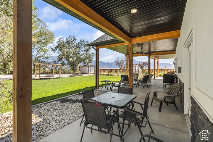 Covered concrete patio featuring wood structural posts, a black tongue-and-groove ceiling, recessed lighting, and stone veneer accents
