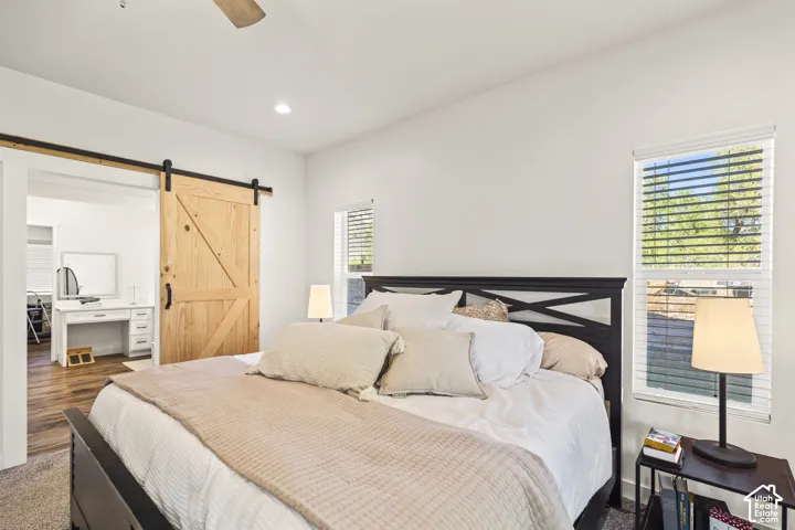 Natural wood sliding barn door, recessed ceiling lighting, dual windows, and wall-to-wall carpeting