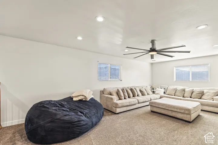 Neutral-toned carpeting, recessed ceiling lighting, a multi-blade ceiling fan, and horizontal window blinds