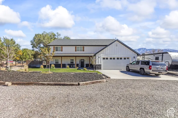 Two-story residence featuring vertical siding, a covered front porch, a multi-car garage, and mountain scenery