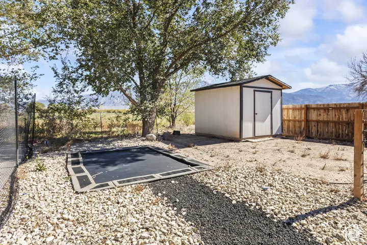 Fenced backyard featuring gravel landscaping, a detached storage shed, and mountain scenery