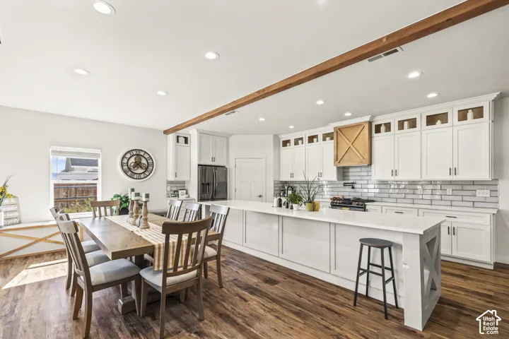 Kitchen featuring white cabinetry, an expansive island with a light-toned countertop, a subway tile backsplash, recessed lighting, and wood-finish flooring