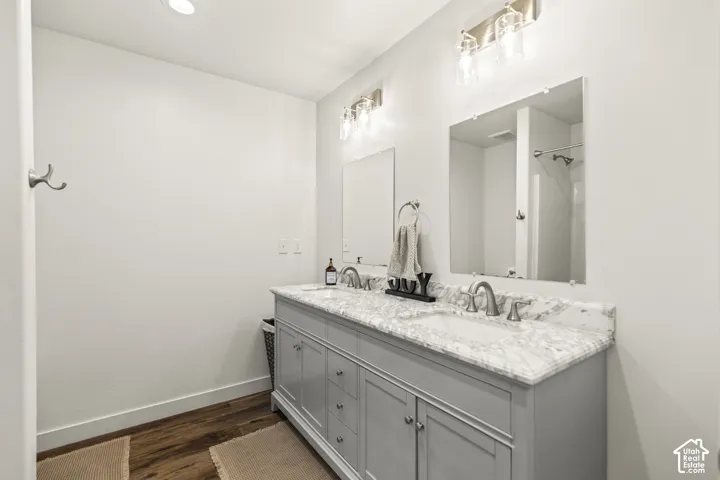 Dual-sink vanity featuring stone-finish countertops, undermount sinks, wood-finish cabinetry, and two wall-mounted light fixtures