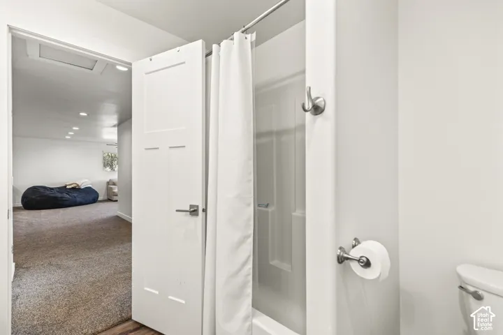 Bathroom featuring a tub-shower combination with a white surround, brushed nickel hardware, and a solid-core panel door with lever-style handle