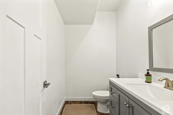 Gray vanity cabinet with a white countertop, integrated sink, brushed metal faucet, and framed wall mirror