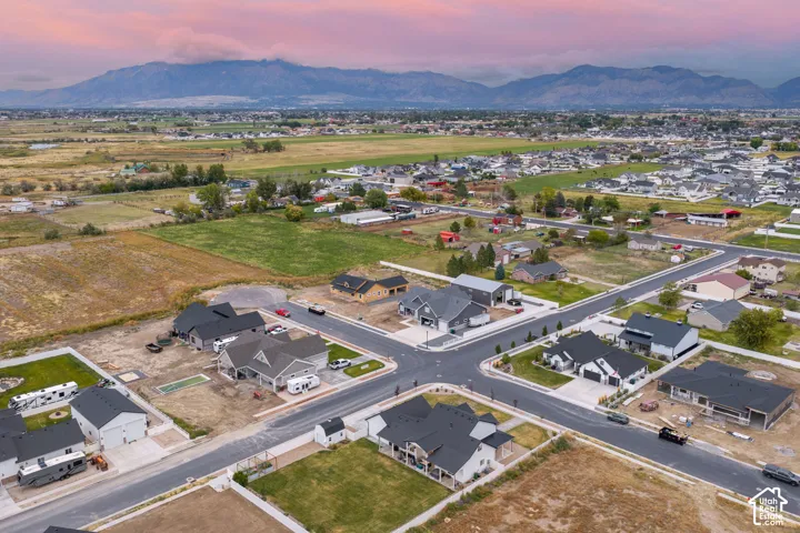 Aerial perspective of a residential development featuring asphalt streets, concrete driveways, and expansive mountain scenery