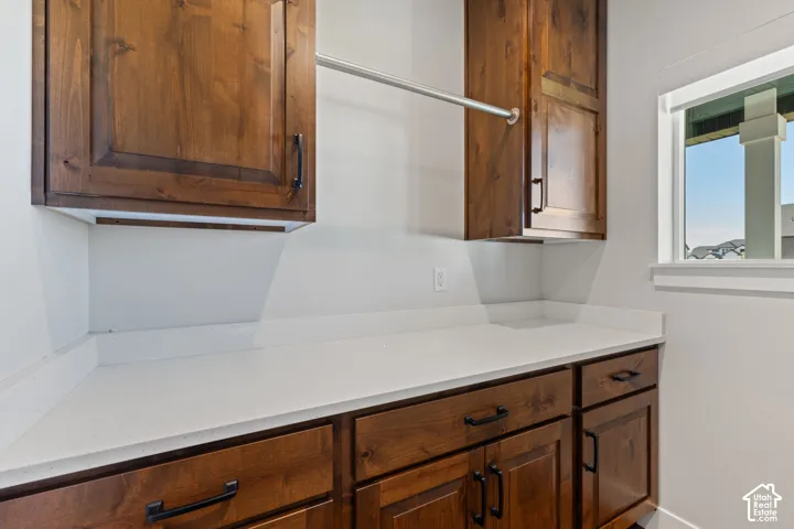 Stained wood cabinetry, white quartz countertop, matte black hardware, and an integrated hanging rod