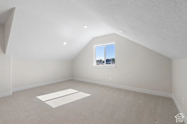 Bedroom with vaulted ceiling featuring recessed lighting, neutral-toned wall-to-wall carpeting, and a single-pane sliding window